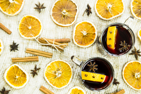 two transparent cups with hot mulled wine and an orange slice among spices of cinnamon and aniseの写真素材