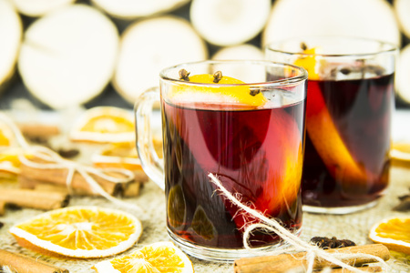 two transparent cups with hot mulled wine and an orange slice among spices of cinnamon and aniseの写真素材