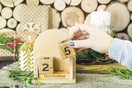 woman puts a date on a wooden calendar - Christmas December 25の写真素材