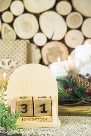 date of the new year on December 31 on a wooden calendar among festive decorations, candles and Christmas tree branchesの写真素材