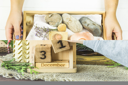 the girl is holding a wooden tray with accessories for spa procedures with a floppy, candles and soap. Flat lay. Top viewの写真素材