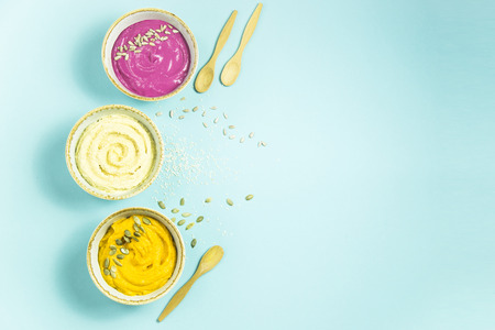 bright appetizers in the form of sauces on a blue background among pumpkin seeds. Hummus, carrot and beetroot sauces. Top view. Flat lay. Copyspaceの写真素材