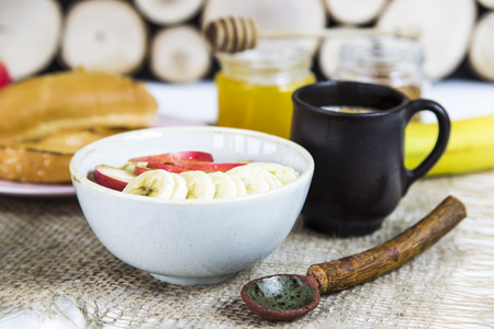 healthy breakfast - oatmeal with fruit in a bowl next to rustic spoonの写真素材