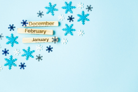 inscriptions of the names of the months on wooden plates - December, January, February, on a blue background among snowflakes and sparkles. Copyspace. Top viewの写真素材