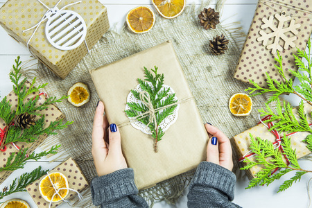 girl holding a gift wrapped for Christmas decorated with a green branchの写真素材