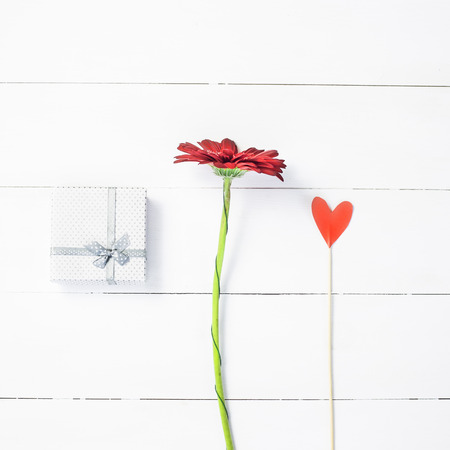 St. Valentine's Day concept. A gift, a red dahlia flower and a paper heart on a stickの写真素材