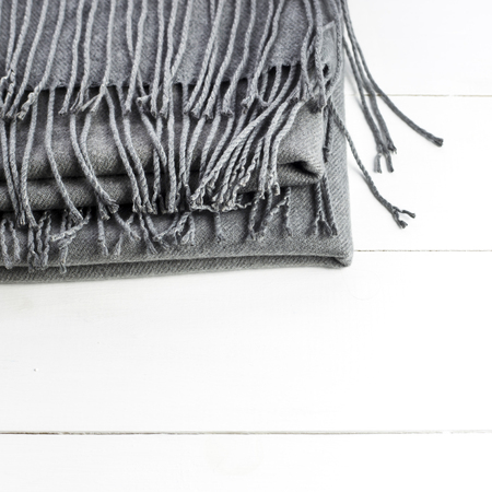 Background texture of the crumpled gray winter fashionable female scarf. On a white wooden tableの写真素材