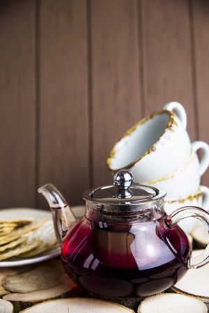 Red tea karkade with berries in a transparent teapot on a wooden table. Rustic styleの写真素材