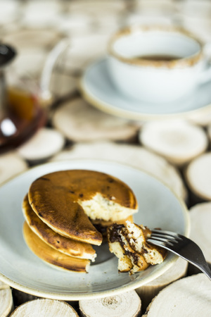 Pancakes with chocolate inside on a wooden table of log cabins. Rustic style. Concept of homemade foodの写真素材