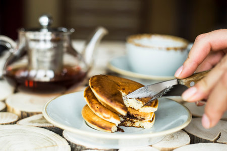 Pancakes with chocolate inside on a wooden table of log cabins. Rustic style. Concept of homemade...