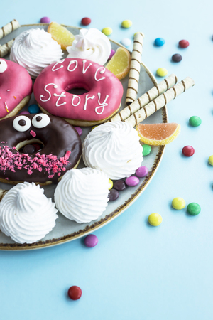 Sweet unhealthy food on a plate - donuts, meringue, sticks, marmalade, chocolate grains. Junk food conceptの写真素材