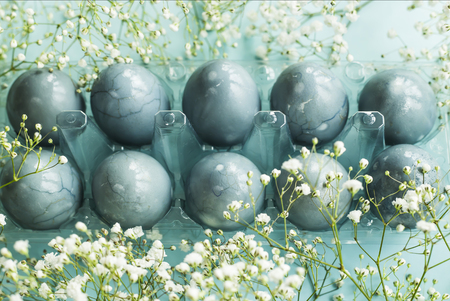 Delicate blue Easter eggs among the flowers of gypsophila on a blue backgroundの写真素材