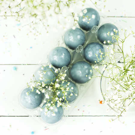 Blue easter eggs on a white table among bouquets of gypsophilaの写真素材