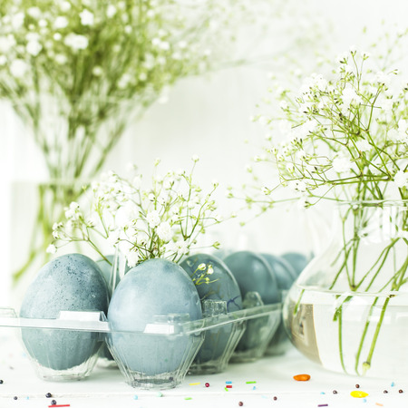 Blue easter eggs on a white table among bouquets of gypsophilaの写真素材