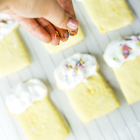 The process of making cookies in the form of pasoks on a white kitchen table. Homemade concept. Woman decorating the product with powderの写真素材