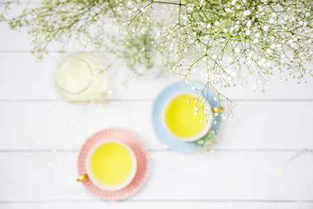 Delicate vintage cups of pink and blue with tea among the white dried flowers of gypsophila. Home interior and still life concept. Top view. Flatlayの写真素材