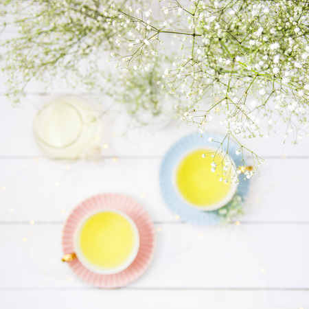 Delicate vintage cups of pink and blue with tea among the white dried flowers of gypsophila. Home interior and still life concept. Top view. Flatlayの写真素材