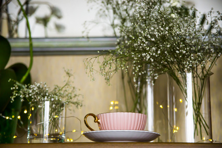 Pink vintage cup with tea on the cupboard near the mirror among the white dry flowers gypsophila. Home interior and still lifeの写真素材