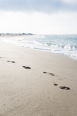 Footprints in the sand by the sea. Summer beach holiday concept. Seasonal trips to the sea or the ocean. Copyspaceの写真素材