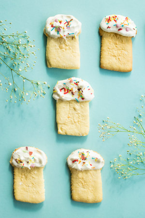 Cookies in the form of Easter cakes on a blue background among the flowers of gypsophila
