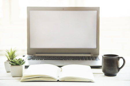 Workplace at the laptop monitor with a notebook on a white table. Minimalistic design. Sunlight - easy tintingの写真素材