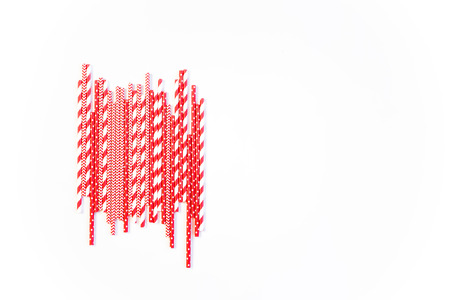 A stack of red and white striped and spotted straws for cocktails on a white background. Festive mood concept. Flat lay, top view, copyspaceの写真素材