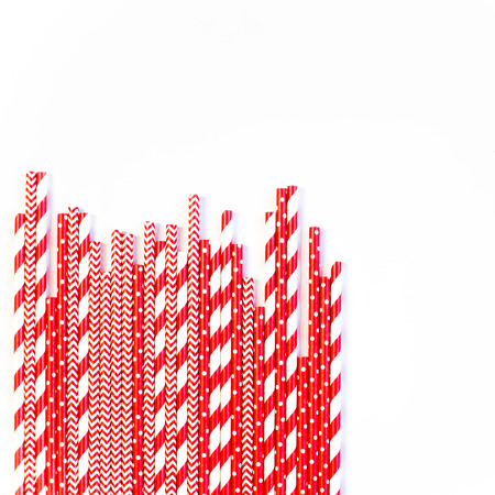 A stack of red and white striped and spotted straws for cocktails on a white background. Festive mood concept. Flat lay, top viewの写真素材