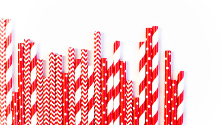A stack of red and white striped and spotted straws for cocktails on a white background. Festive mood concept. Flat lay, top viewの写真素材