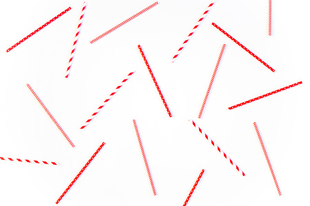 Scattered red and white striped and spotted straws for cocktails on a white background. Festive mood concept. Flat lay, top viewの写真素材