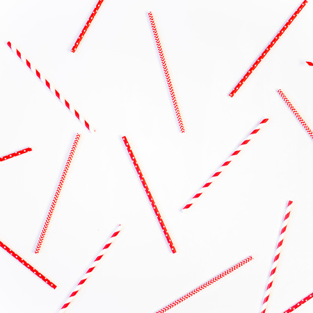 Scattered red and white striped and spotted straws for cocktails on a white background. Festive mood concept. Flat lay, top viewの写真素材