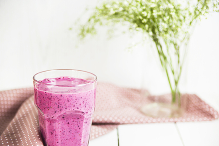 Banana currant smoothies in a glass on a white table next to a pink napkin in speckles. Against the background of delicate white and green colorsの写真素材