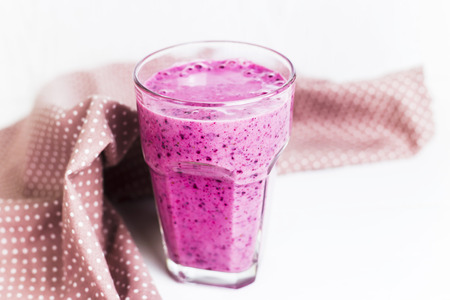 Banana currant smoothies in a glass on a white table next to a pink napkin in specklesの写真素材