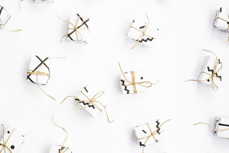 Small gift boxes of white color with black geometric patterns tied with twine. On a white background. Top view, flat layの写真素材