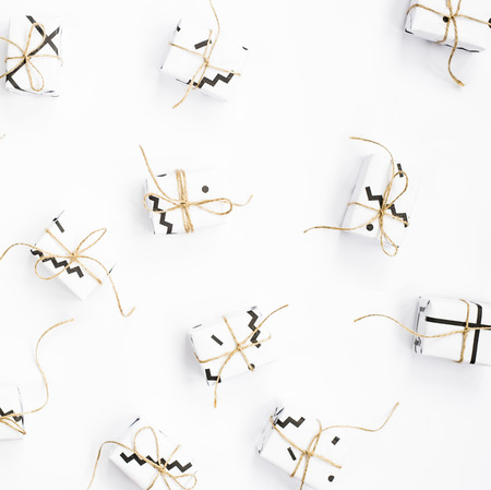 Small gift boxes of white color with black geometric patterns tied with twine. On a white background. Top view, flat layの写真素材