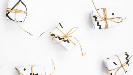 Small gift boxes of white color with black geometric patterns tied with twine. On a white background. Top view, flat layの写真素材