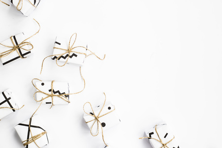 Small gift boxes of white color with black geometric patterns tied with twine. On a white background. Flat lay, Top view, copyspaceの写真素材