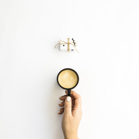 A cup of coffee and one small minimalist gift on a white background. Flat lay, top viewの写真素材