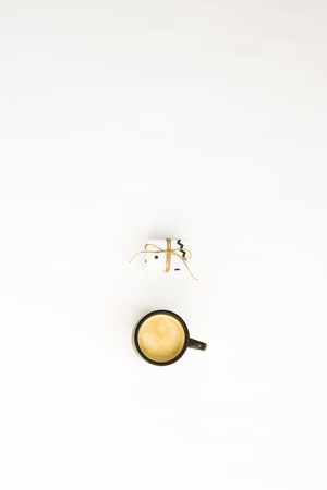 A cup of coffee and one small minimalist gift on a white background. Copyspace.  Flat lay, top viewの写真素材