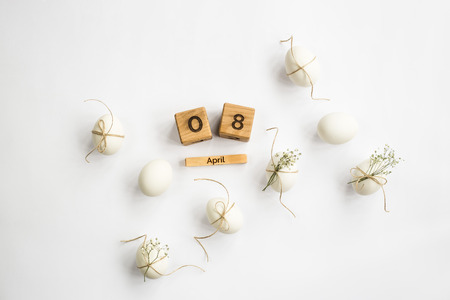 Easter white eggs are minimalistically decorated with twine and gypsophila. With a wooden calendar. 08 April 2018. Easter. Top view, flat layの写真素材