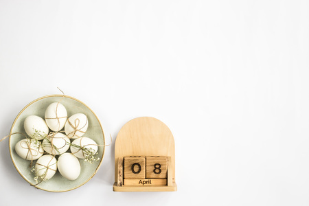 Wooden Calendar - April 08 - the date of Easter in 2018. Next to the plate with white minimalistic Easter eggs. Top view, flat lay, copyspaceの写真素材