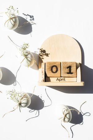 Wooden calendar - April 1 - the date of the Catholic Easter in 2018. Next to the white minimalistic Easter eggs. Flat lay, top viewの写真素材