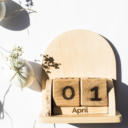 Wooden calendar - April 1 - the date of the Catholic Easter in 2018. Next to the white minimalistic Easter eggs. Flat lay, top viewの写真素材