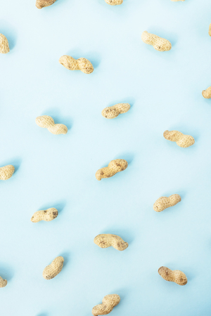 Natural whole peanuts in a shell on a blue background. Healthy vegan food concept. Flat lay, top viewの写真素材