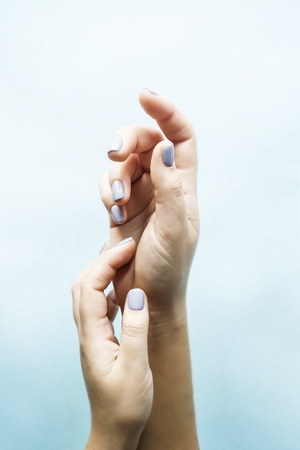 Blue manicure on female nails on a blue background. Trend for gentle pastel colors. Beauty and personal care conceptの写真素材