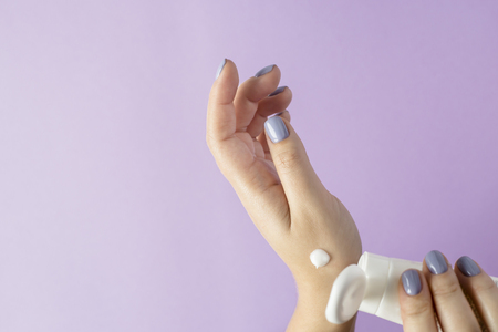 Female hands with a blue manicure hold a hand cream. Female hand care. Beauty and care procedures conceptの写真素材