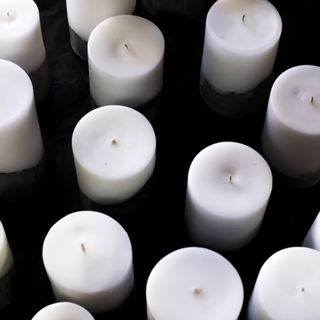 A lot of big white round candles of different size on a black background. Sale of minimalist candles for the interiorの写真素材