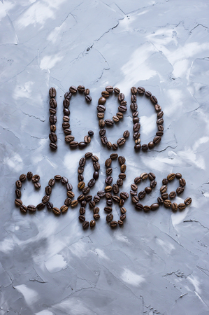 Inscription "ice coffee" from coffee beans on a gray concrete background. Summer cooling drinkの写真素材