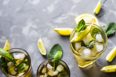 A few glass glasses with a cold tea with ice, mint and lemon on a gray concrete background. Summer cooling drink. Top view, flat lay, copyspaceの写真素材