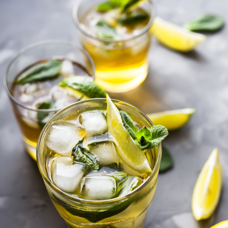 A few glass glasses with a cold tea with ice, mint and lemon on a gray concrete background. Summer cooling drinkの写真素材