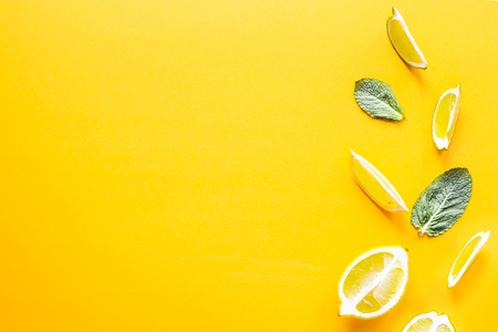 Pieces of lemon, lime and green mint leaves on a yellow background. Summer products for making lemonade. Top view, flat lay, copyspaceの写真素材